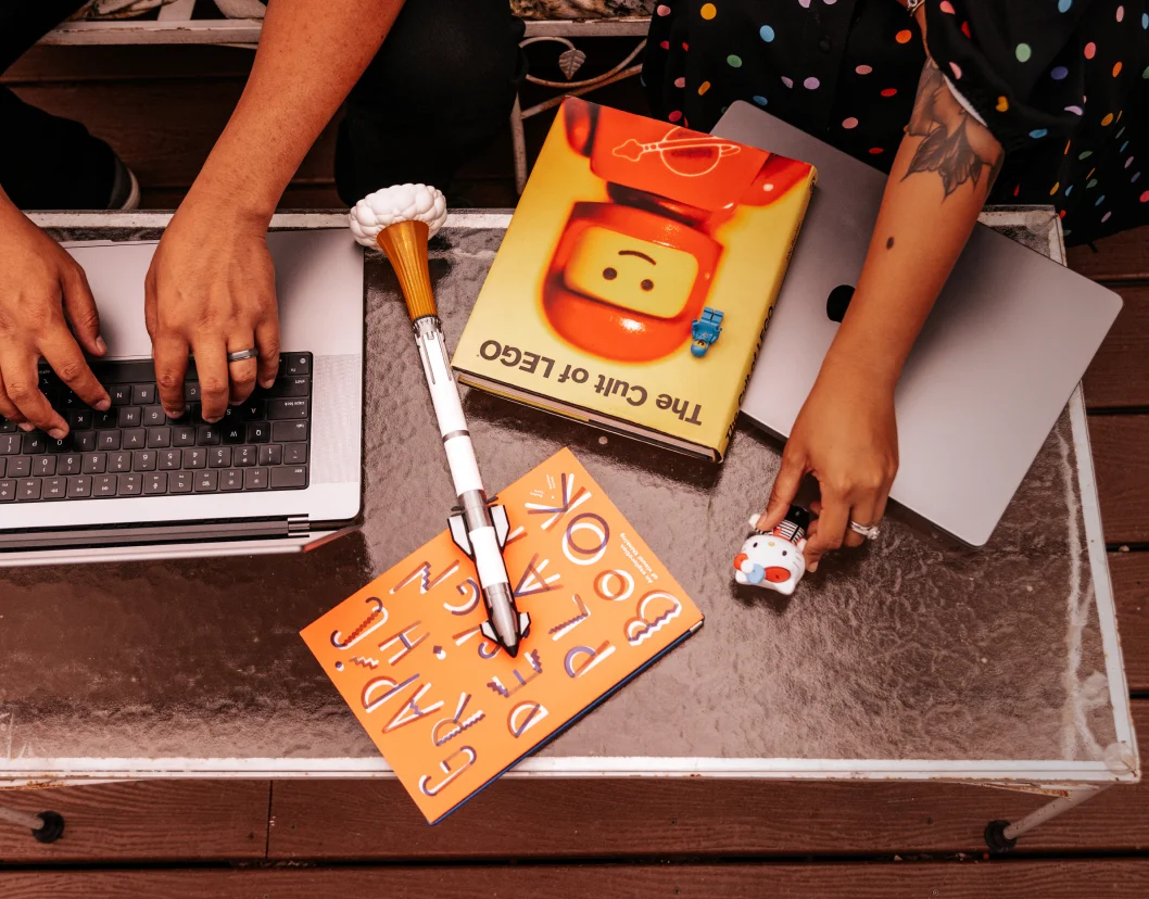 Flatlay of laptops, design books, and creative tools on the studio desk